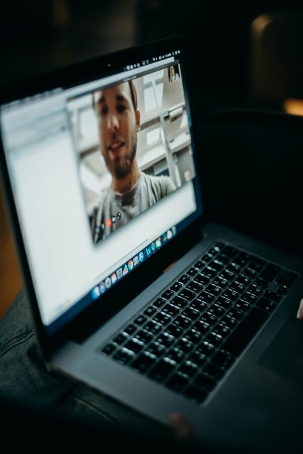 Close-up of a person engaged in a video call on a laptop indoors, showcasing modern technology.